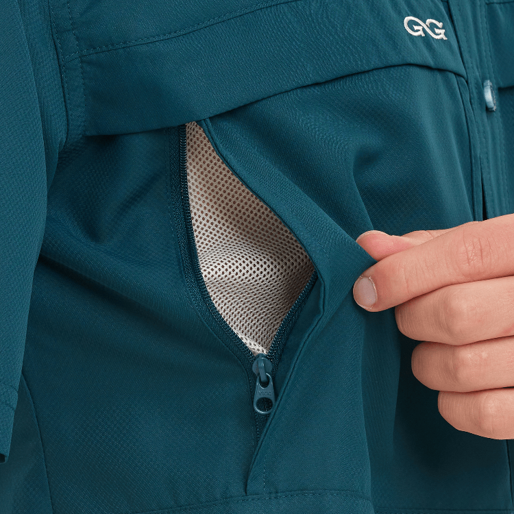 Teal jacket with a hand opening a mesh pocket, featuring a brand logo.