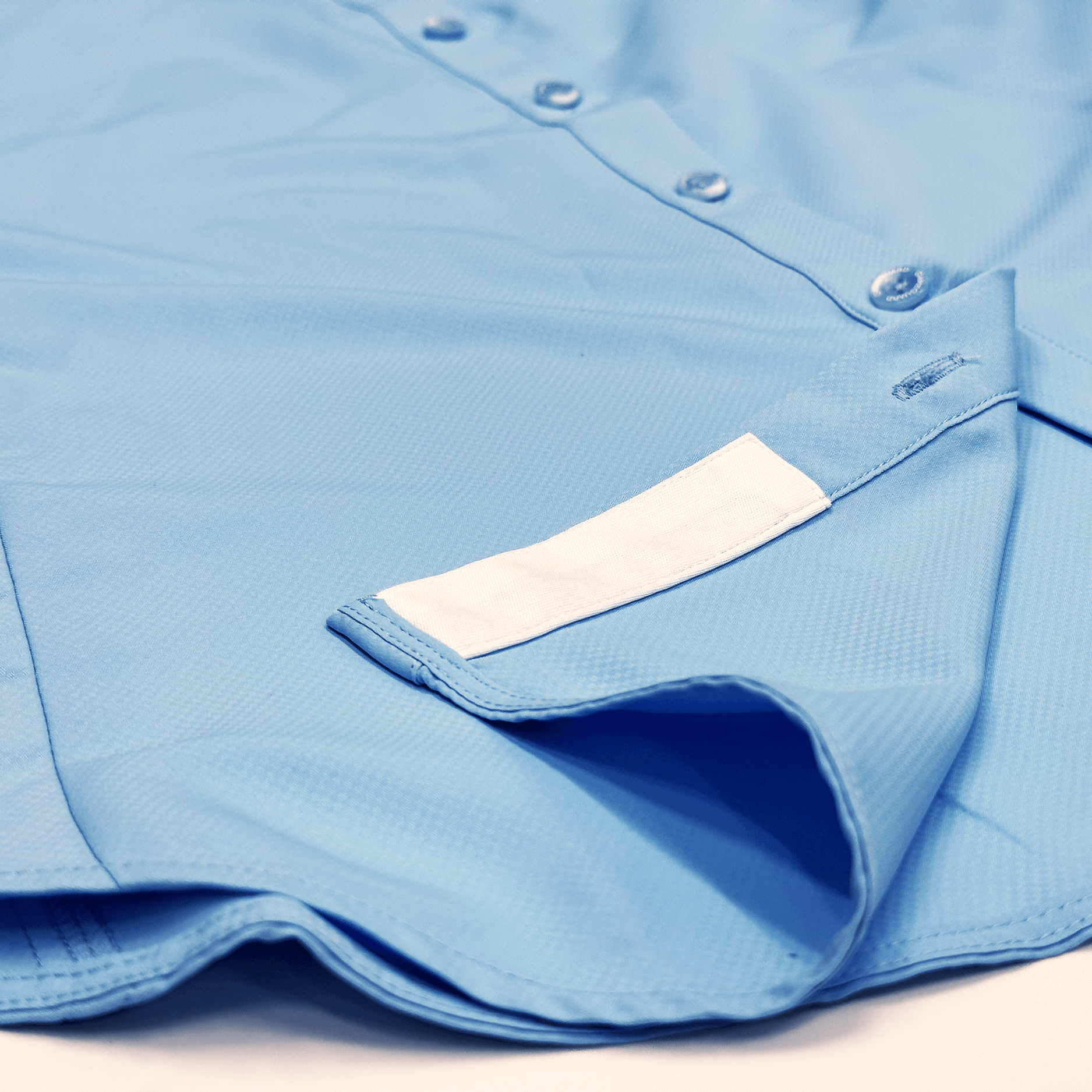 Close-up of a blue shirt with a white label on a light background