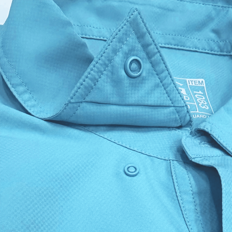 Close-up of a blue shirt with a button and label detail