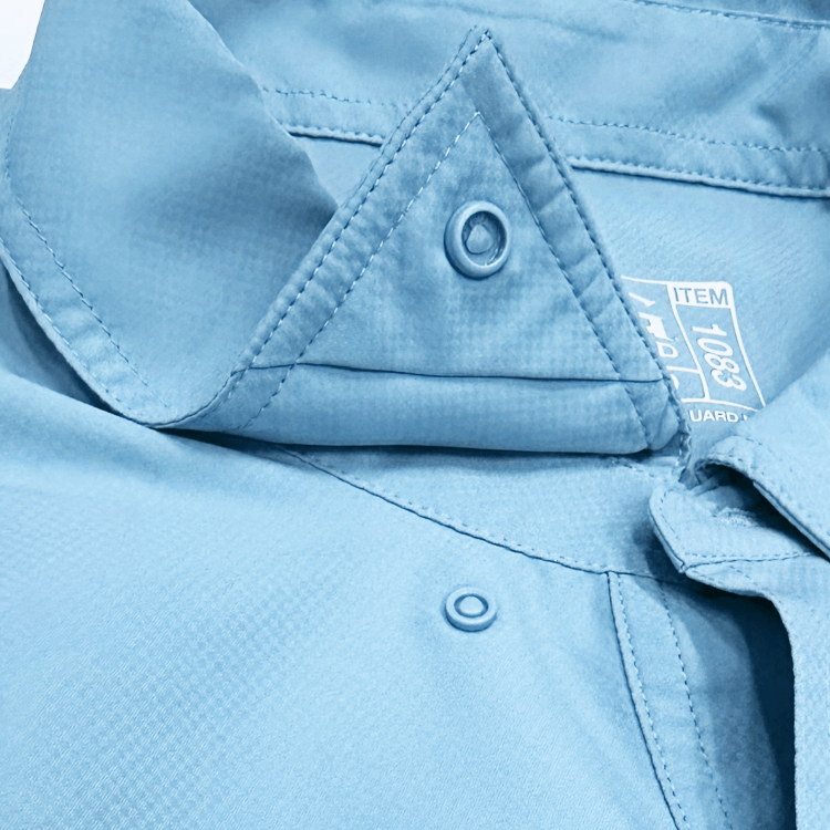 Close-up of a light blue shirt with a triangle pocket and button details.