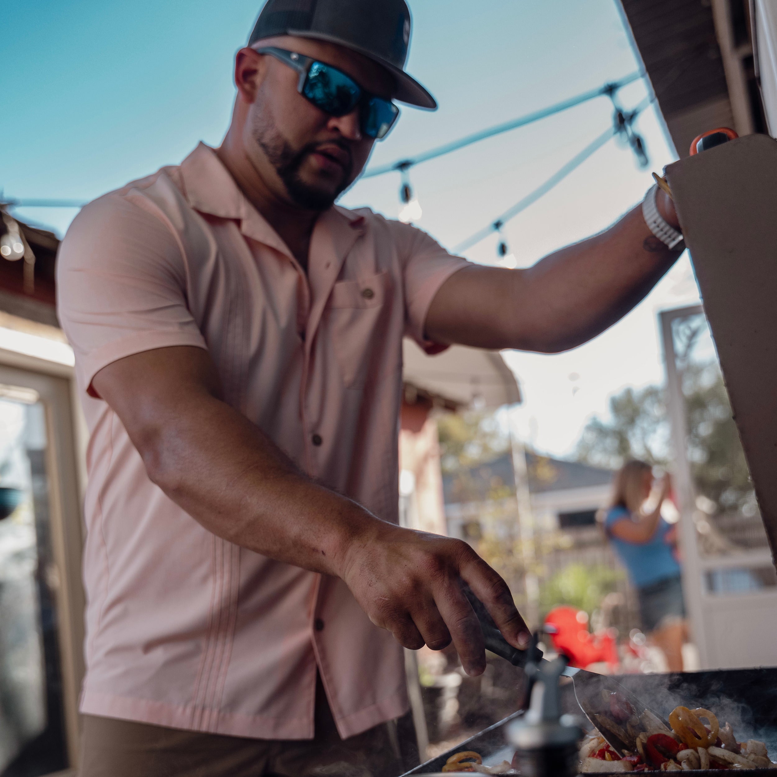 Man grilling outdoors with a casual setting in the background