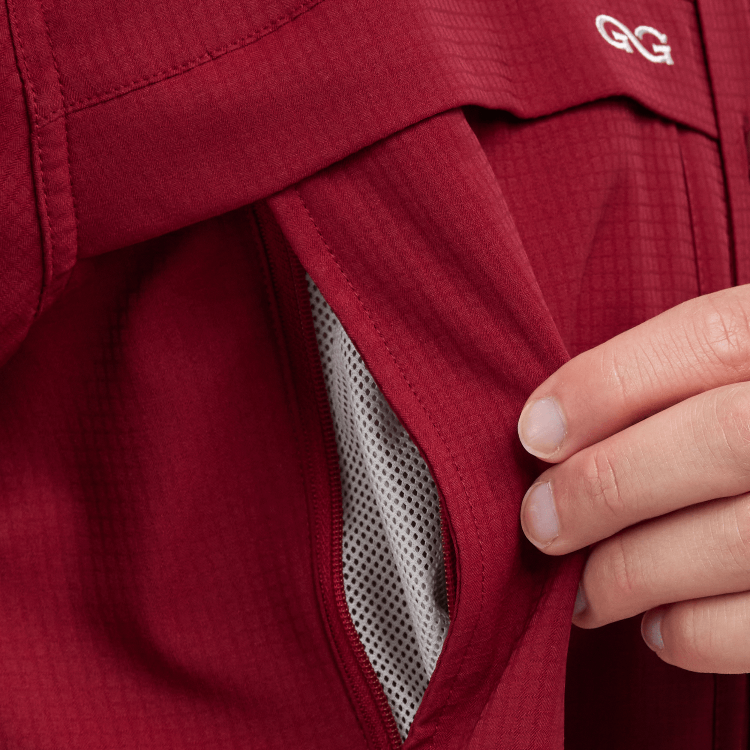 Close-up of a red jacket with a hand adjusting the hood, featuring a brand logo.