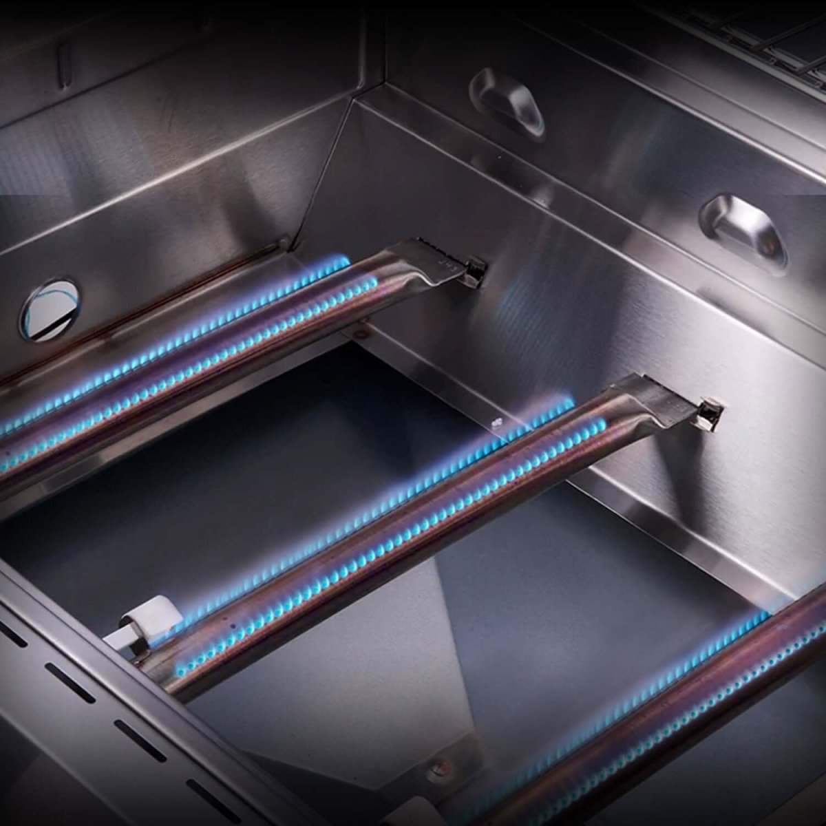 Close-up of a gas grill with lit burners on a reflective surface