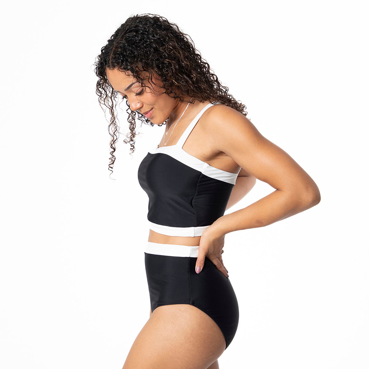Woman wearing a black and white sports bra and shorts on a white background