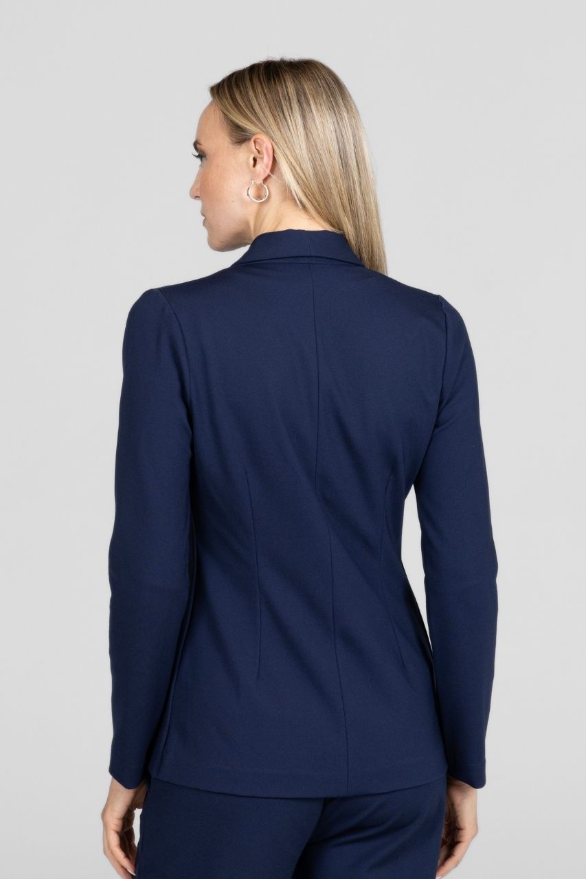 Person wearing a navy blue blazer and pants on a light gray background