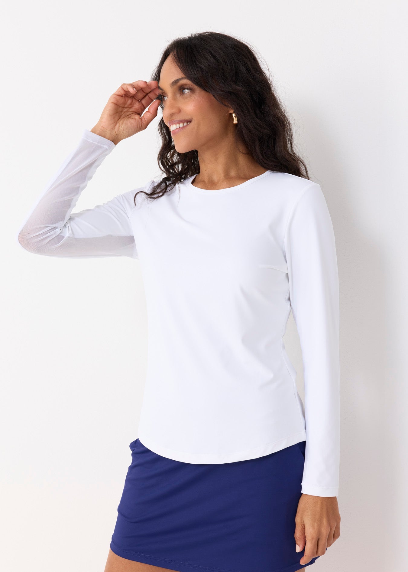 Woman wearing a white long-sleeve top and blue skirt against a white background