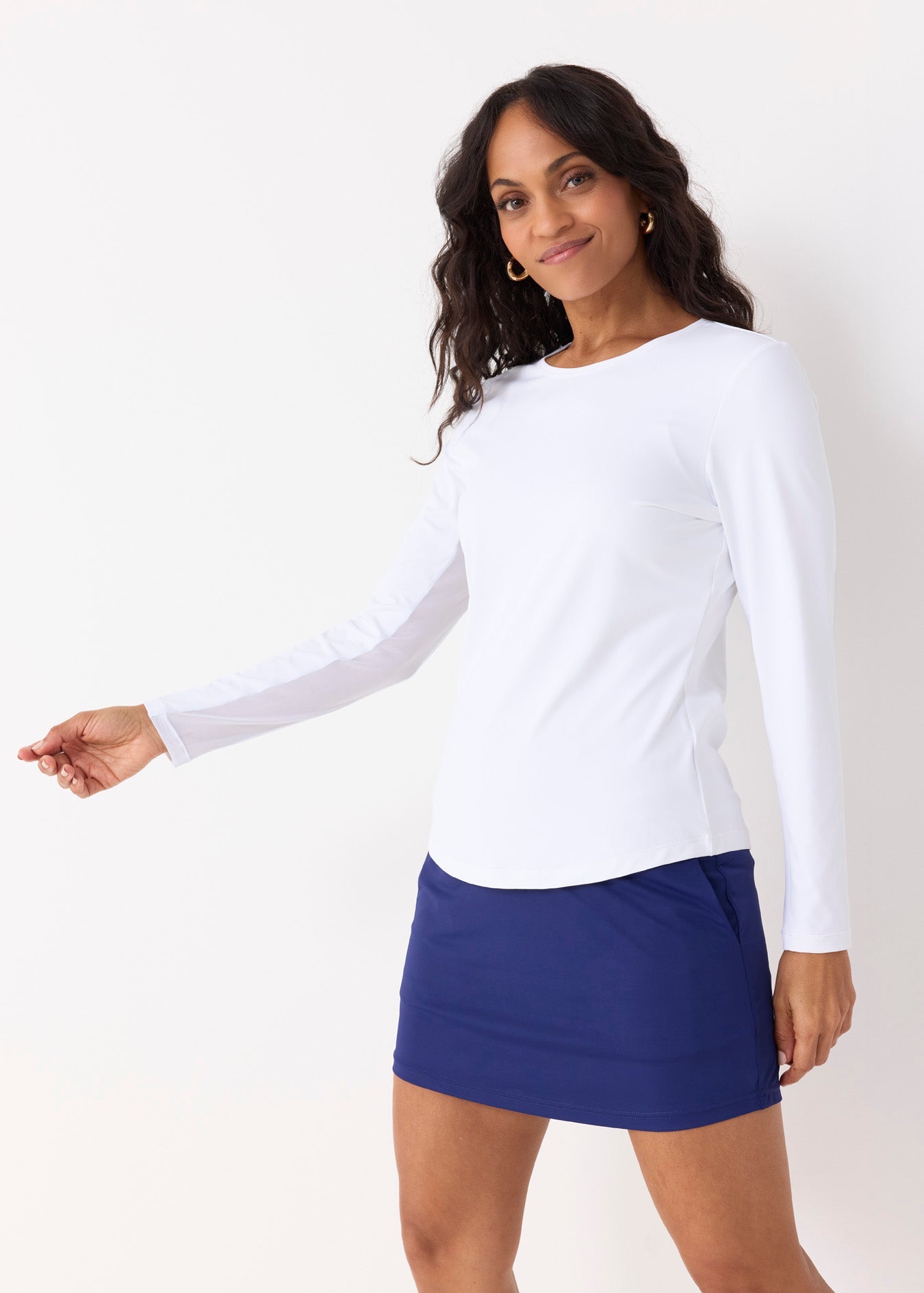 Woman wearing a white long-sleeve top and blue skirt on a white background