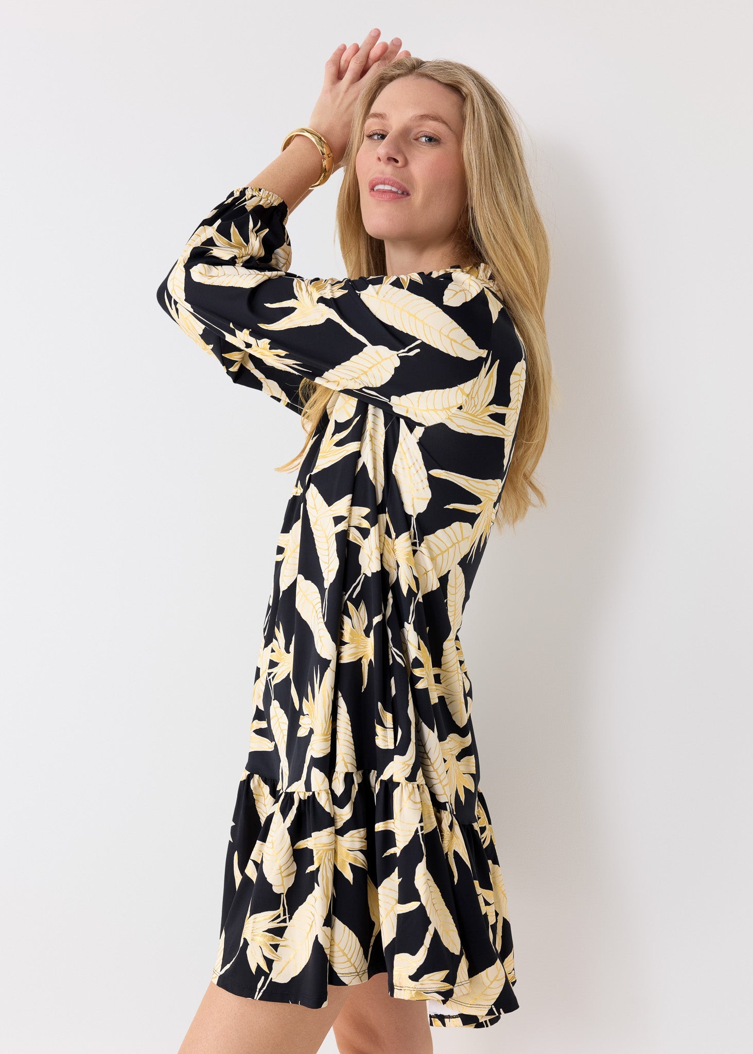 Woman wearing a black dress with yellow floral pattern against a white background