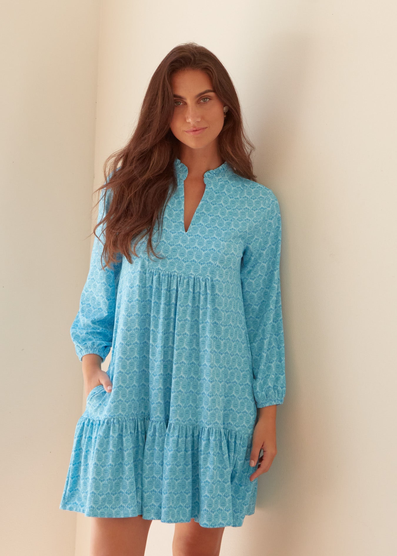 Woman wearing a blue patterned dress against a beige background