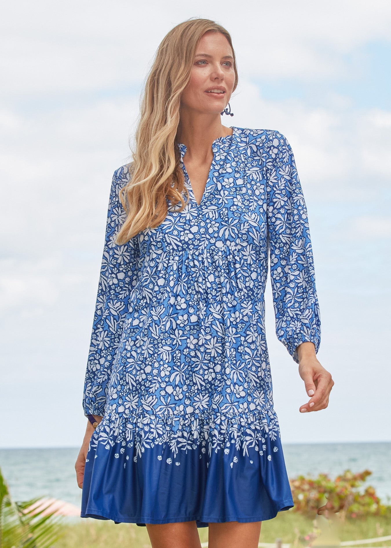 Woman wearing a blue floral dress standing by the ocean