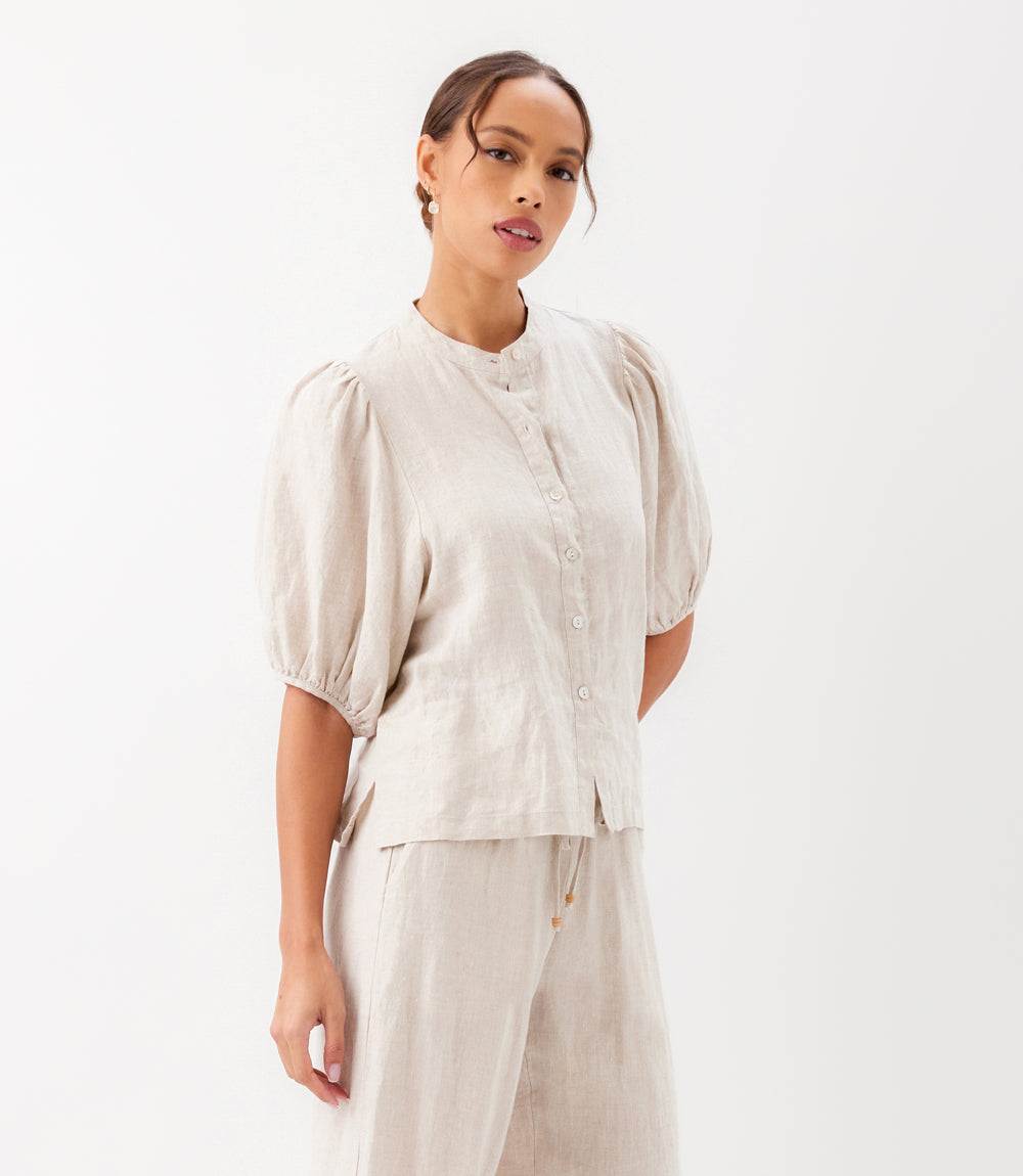 Woman wearing a beige top and pants on a white background