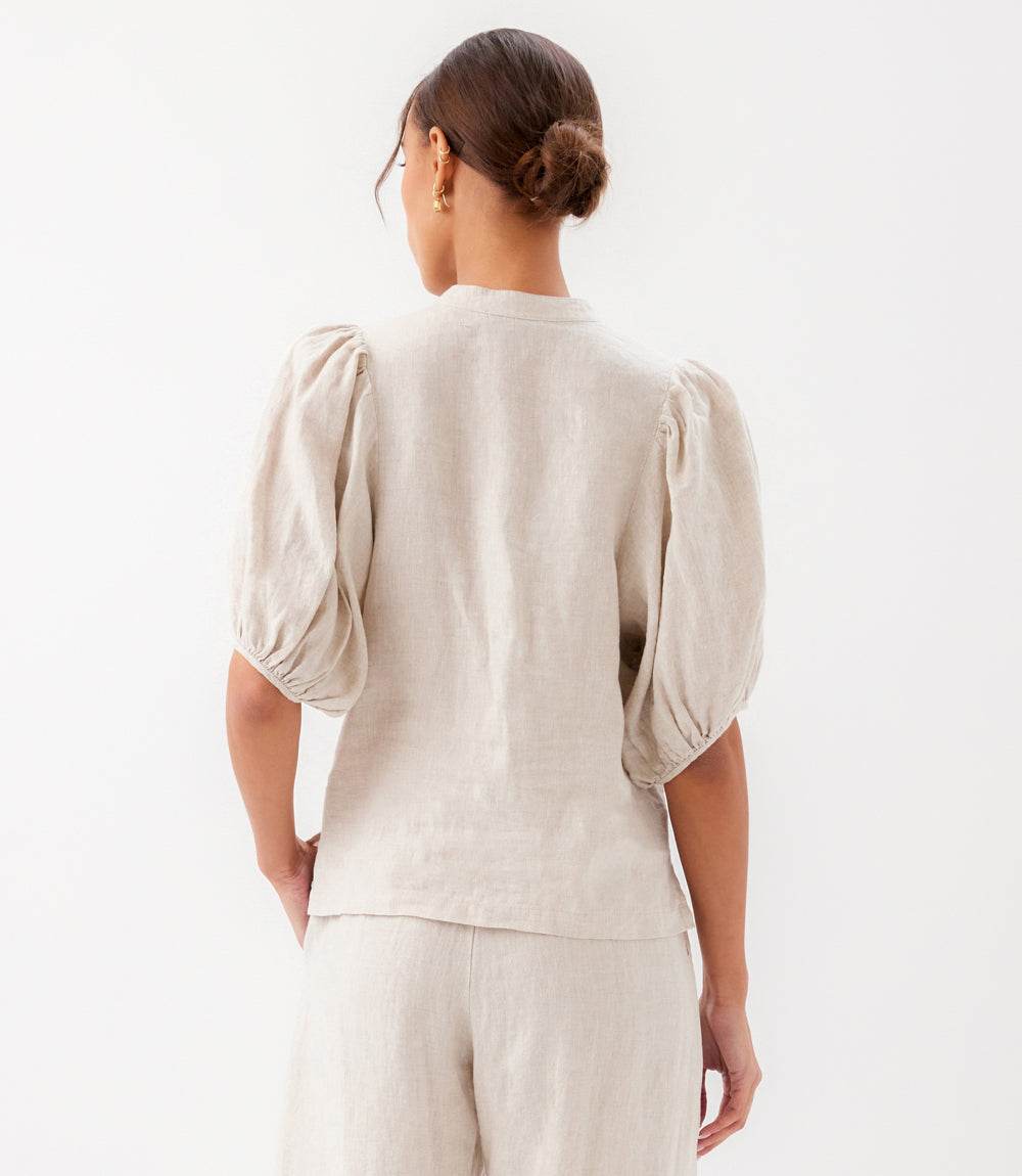 Woman wearing a beige blouse with puffed sleeves on a white background