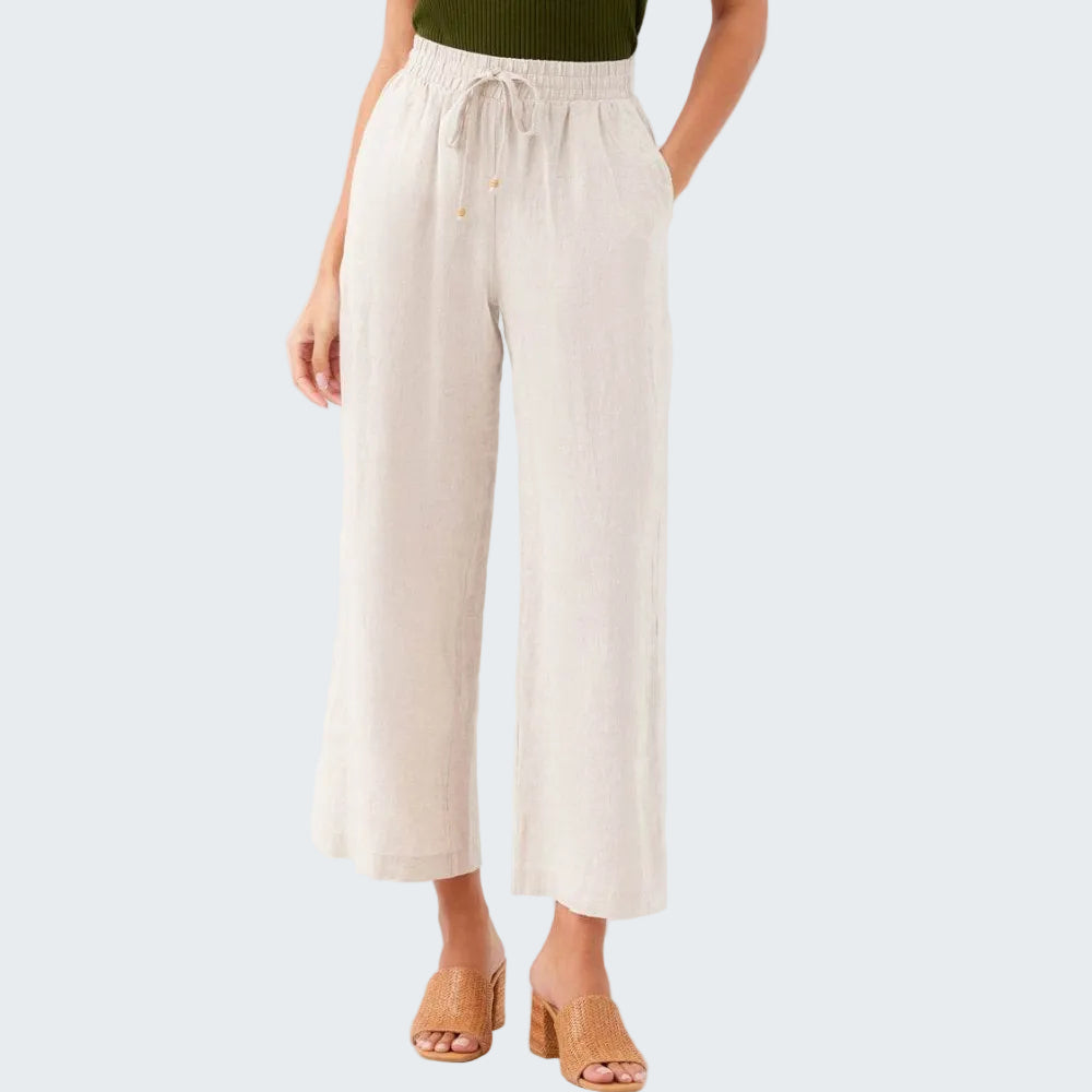 Person wearing beige wide-leg pants on a white background