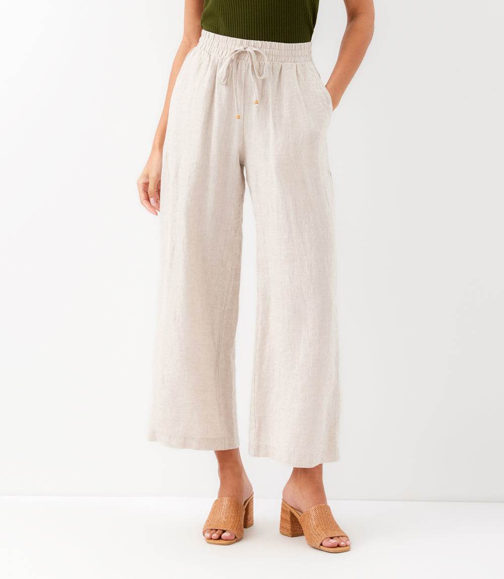 Person wearing beige wide-leg pants on a white background
