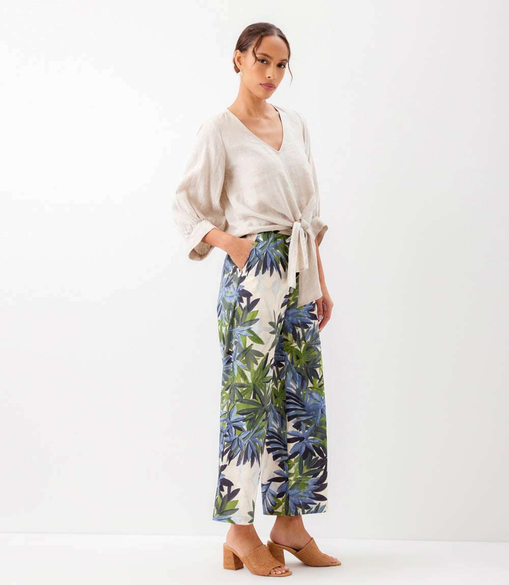 Woman wearing a white top and blue floral pants on a white background