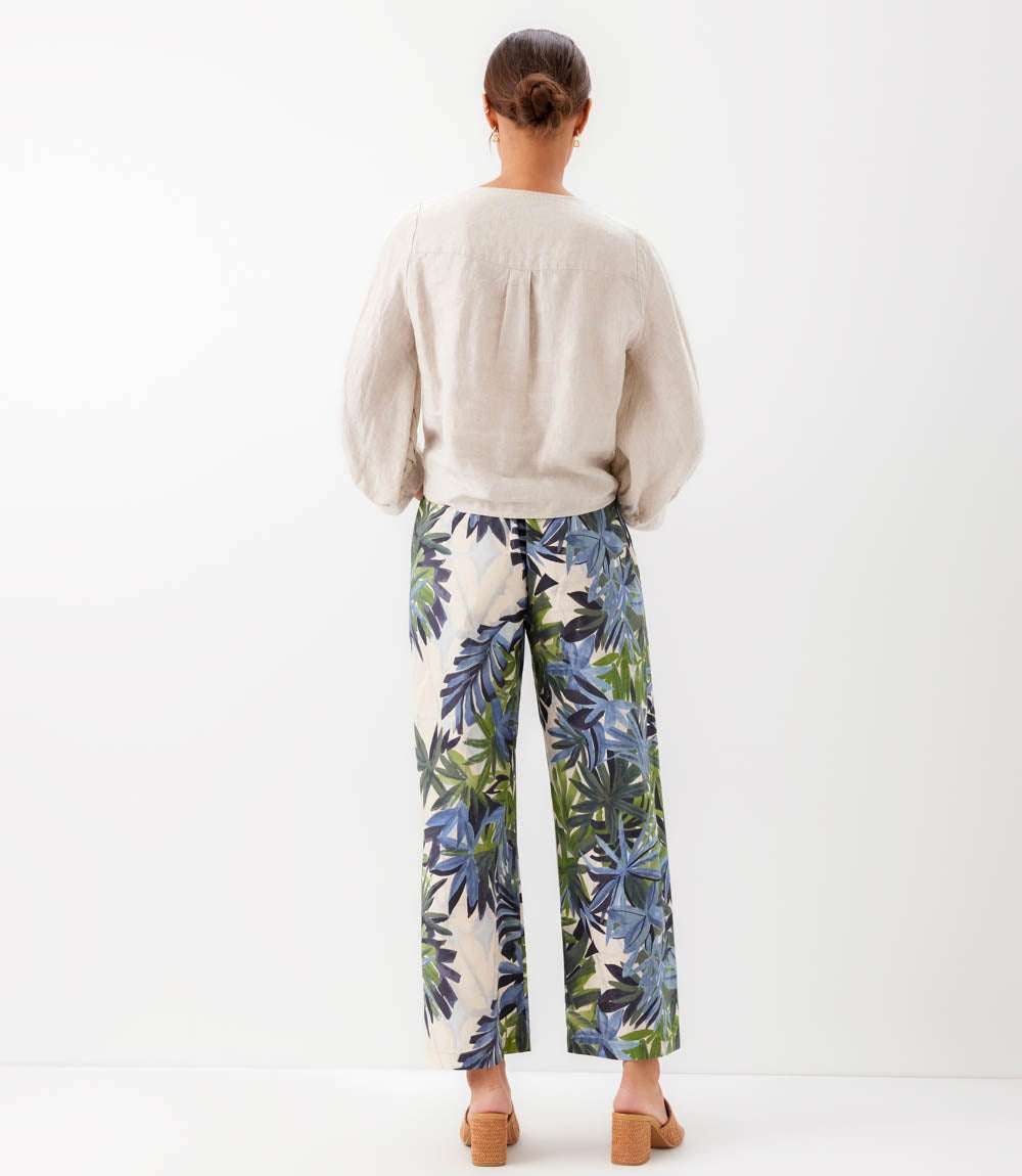 Person wearing a beige sweater and tropical print pants on a white background