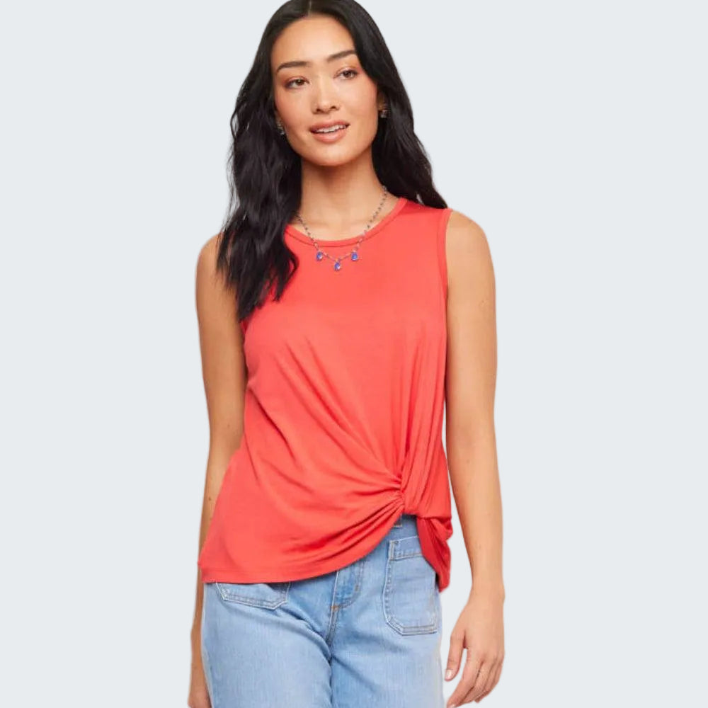 Woman wearing a coral sleeveless top with a knot detail and light blue jeans on a white background