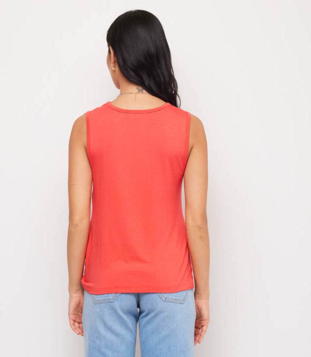 Person wearing a red sleeveless top and blue jeans on a white background