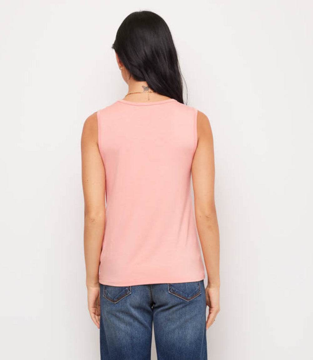 A woman viewed from the back wearing a light pink sleeveless top and blue jeans against a plain white background.
