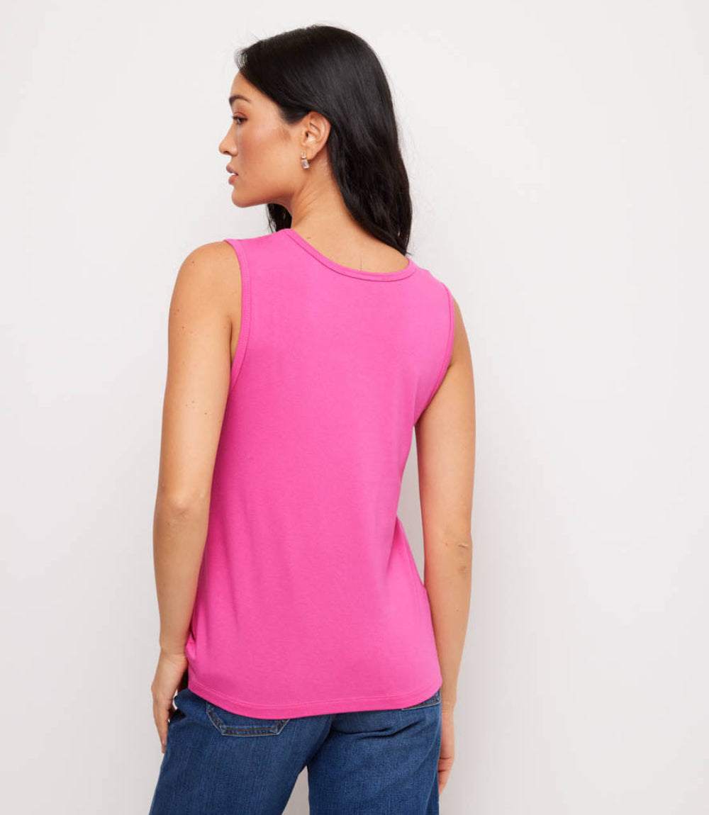 Woman wearing a bright pink sleeveless top and blue jeans against a plain background