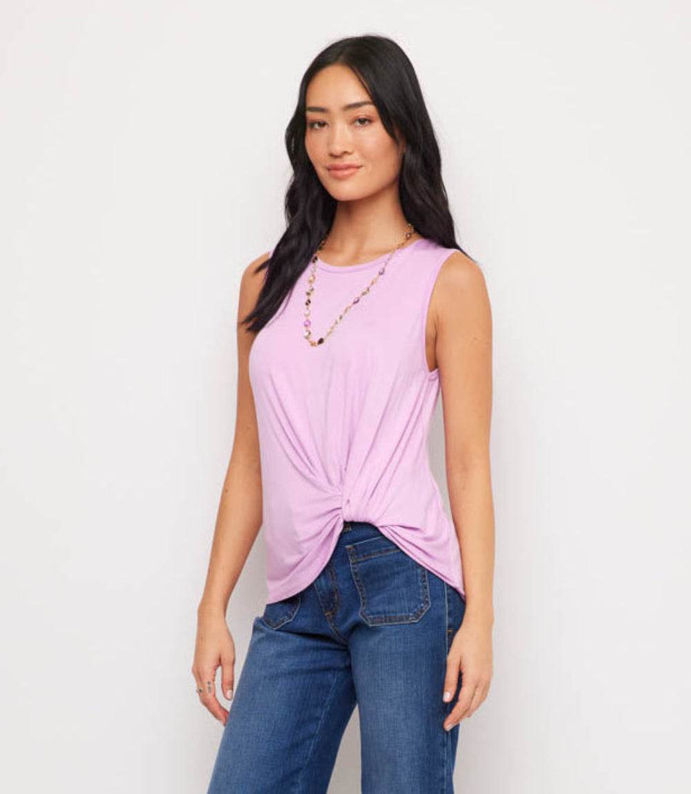 Woman wearing a pink sleeveless top and blue jeans on a white background