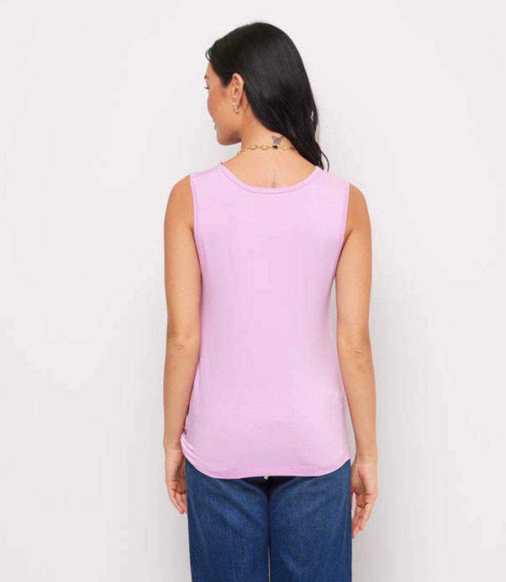 Woman wearing a pink sleeveless top and blue jeans against a white background