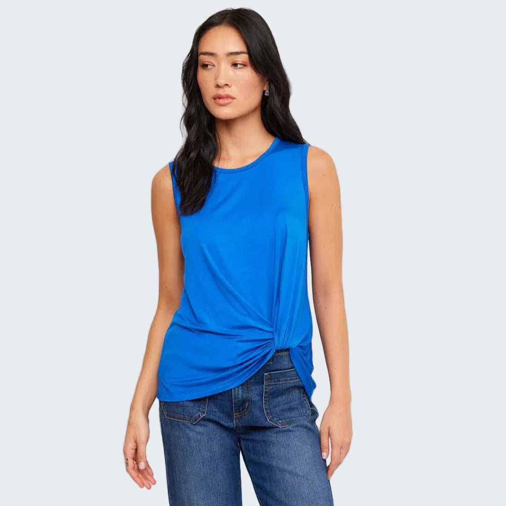 Woman wearing a blue sleeveless top and jeans against a white background