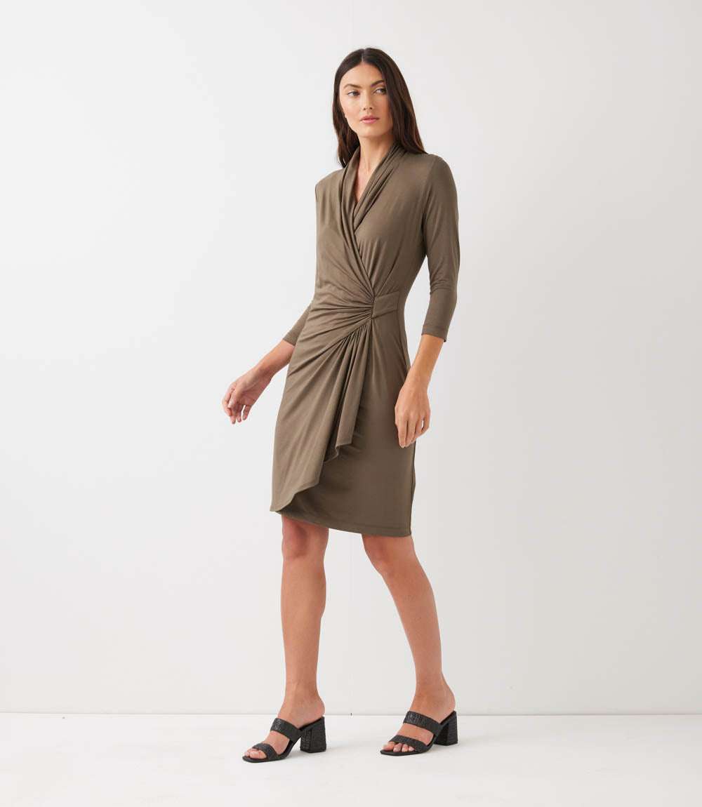Woman wearing a brown dress with a knot detail on a white background