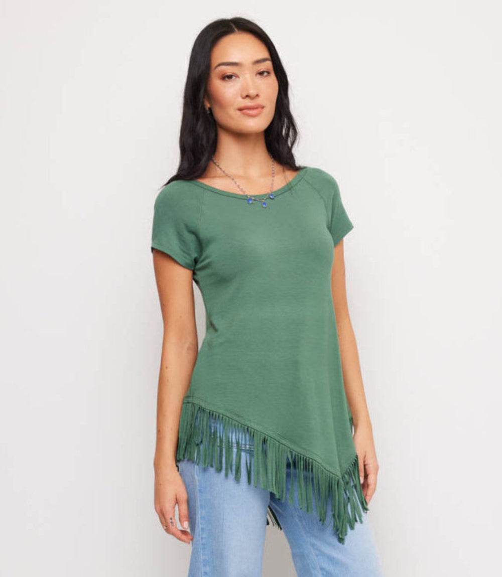 Woman wearing a green tunic with fringe details on a plain background