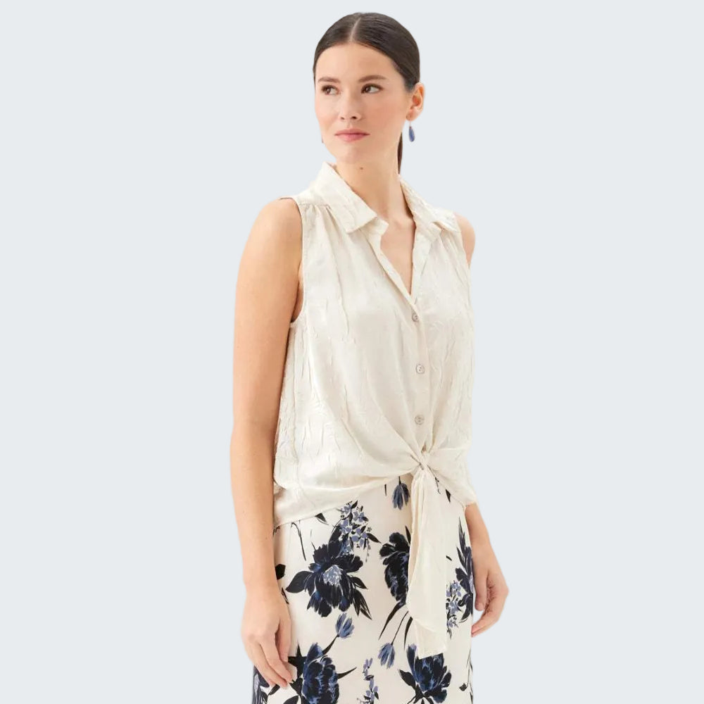 Woman wearing a sleeveless white blouse with a floral skirt on a white background