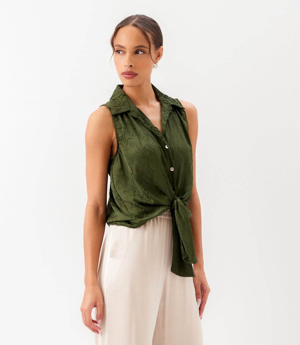 Woman wearing a green sleeveless top with a white background