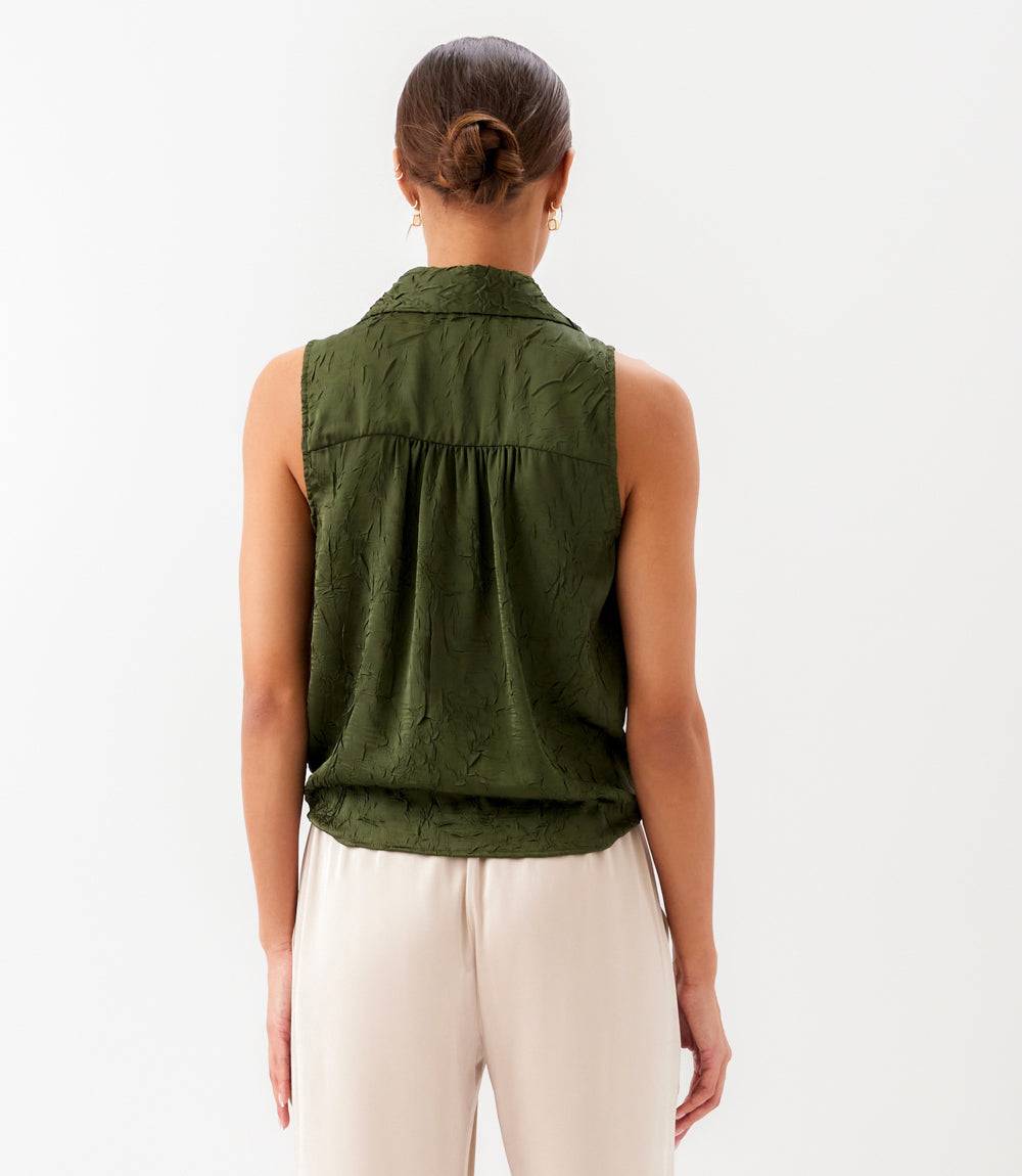 Person wearing a green sleeveless vest on a white background