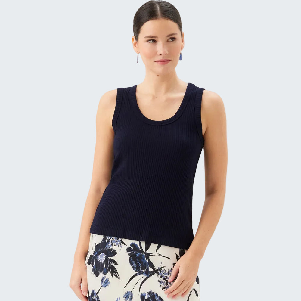 Woman wearing a navy sleeveless top and floral skirt on a light gray background