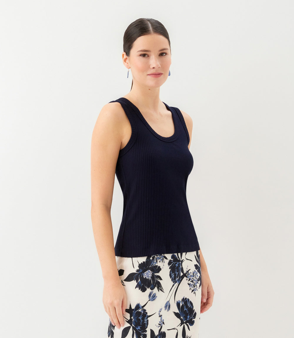 Woman wearing a black sleeveless top and floral skirt on a white background