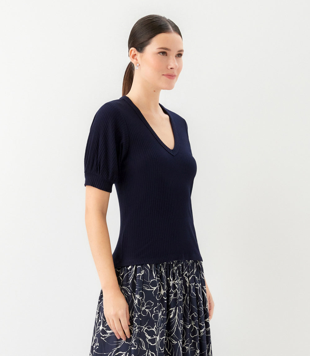 Woman wearing a navy blue top with a plain background