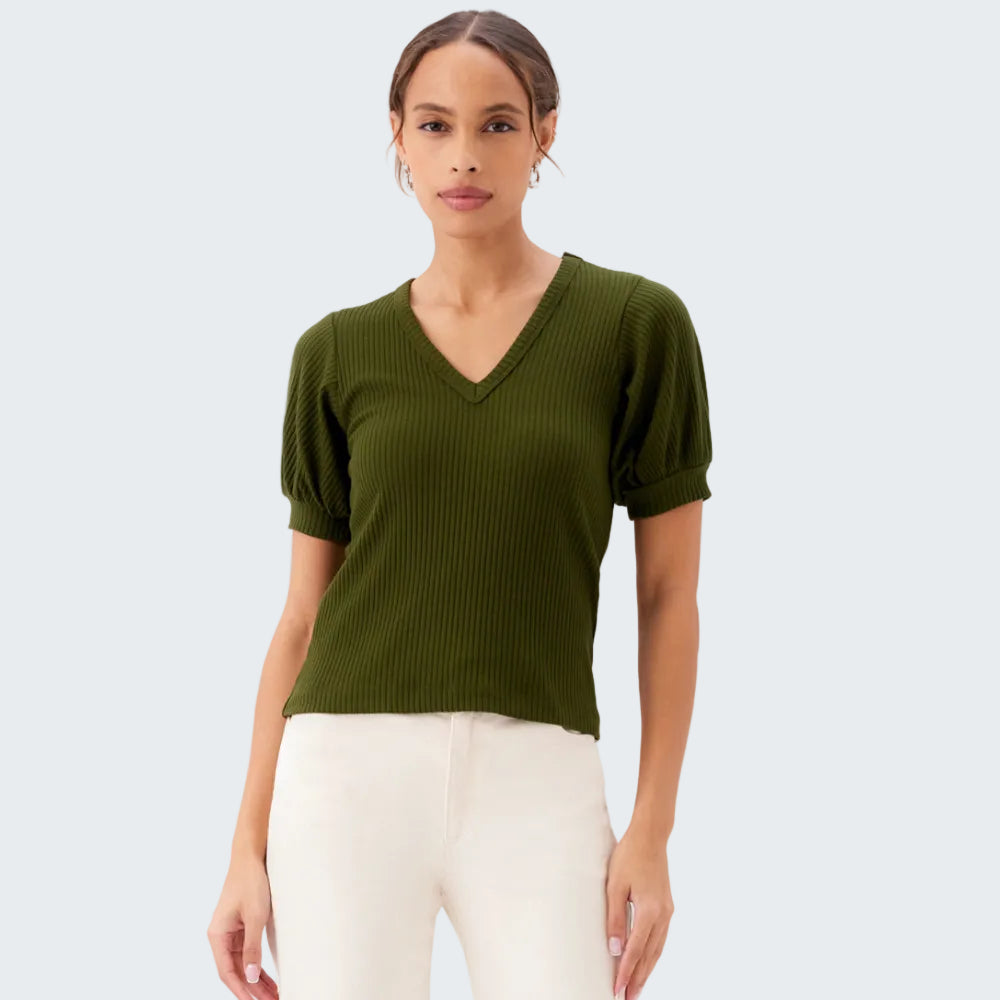 Woman wearing a green ribbed sweater and white pants on a white background