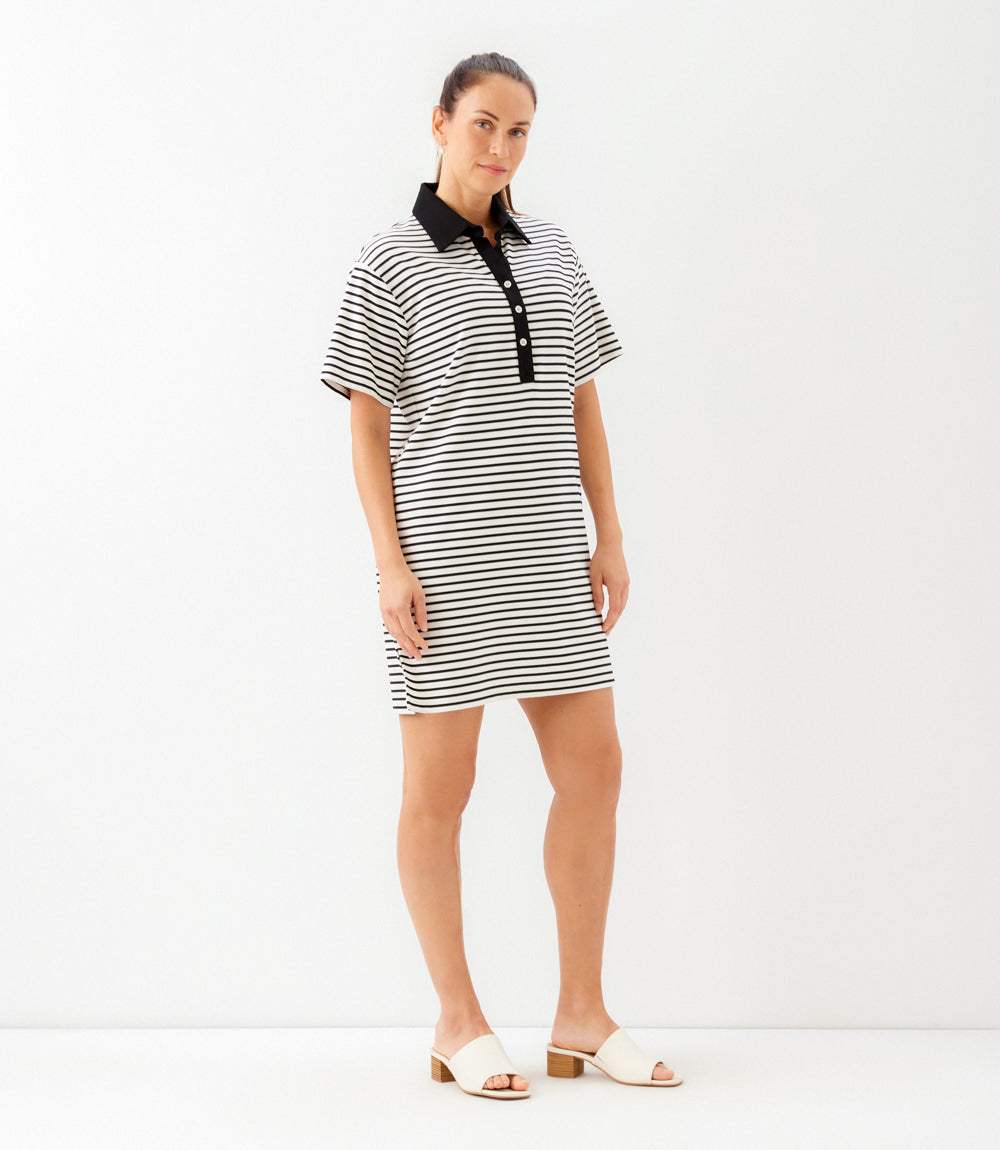 Woman wearing a black and white striped dress with a black collar on a white background