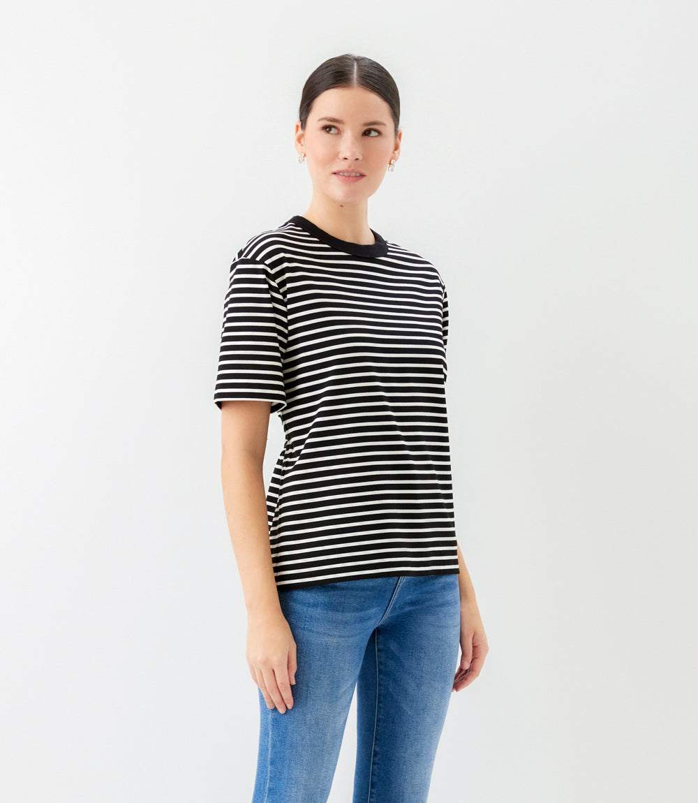 Woman wearing a black and white striped shirt and blue jeans on a white background
