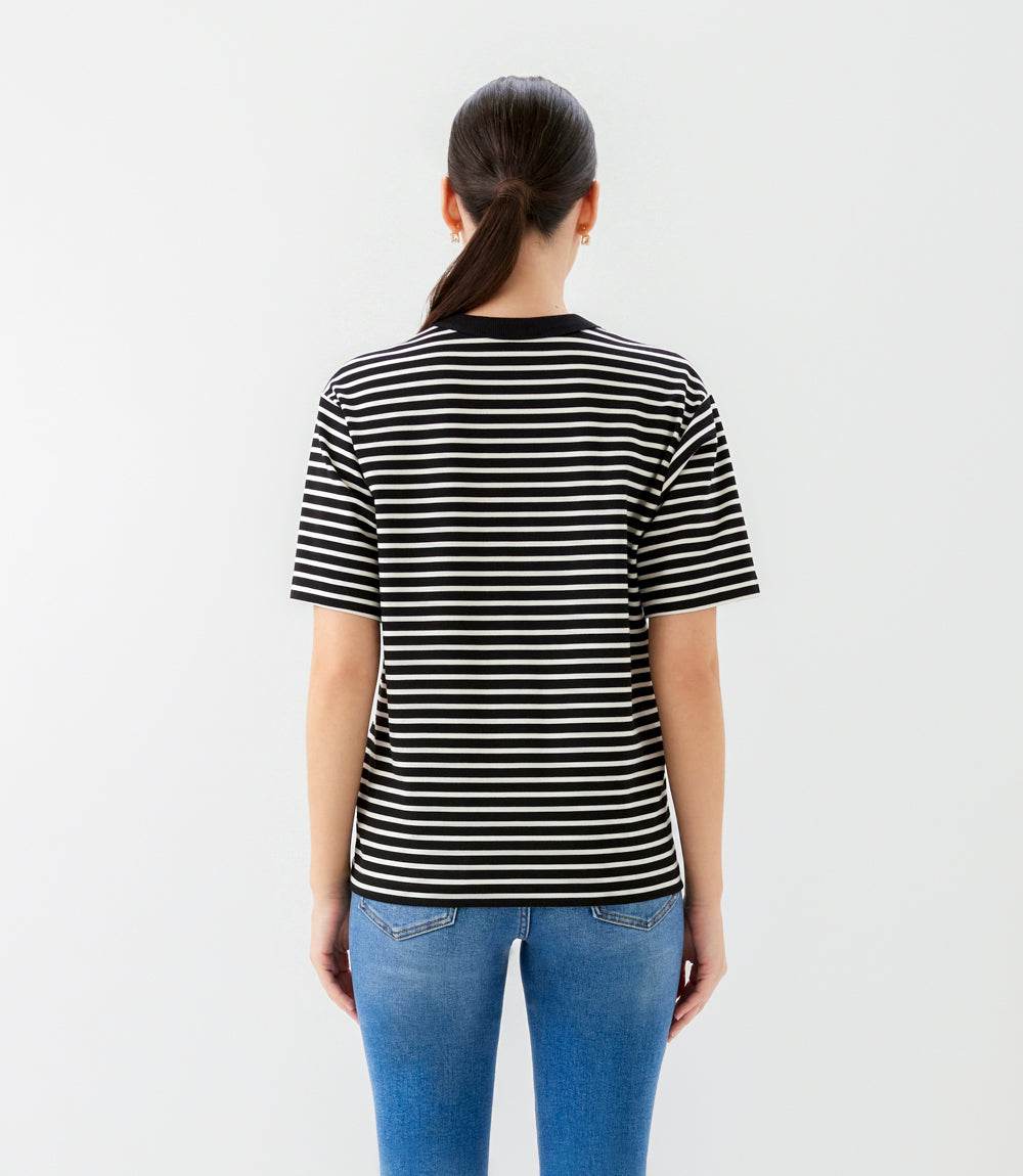 Person wearing a black and white striped t-shirt and blue jeans on a light gray background