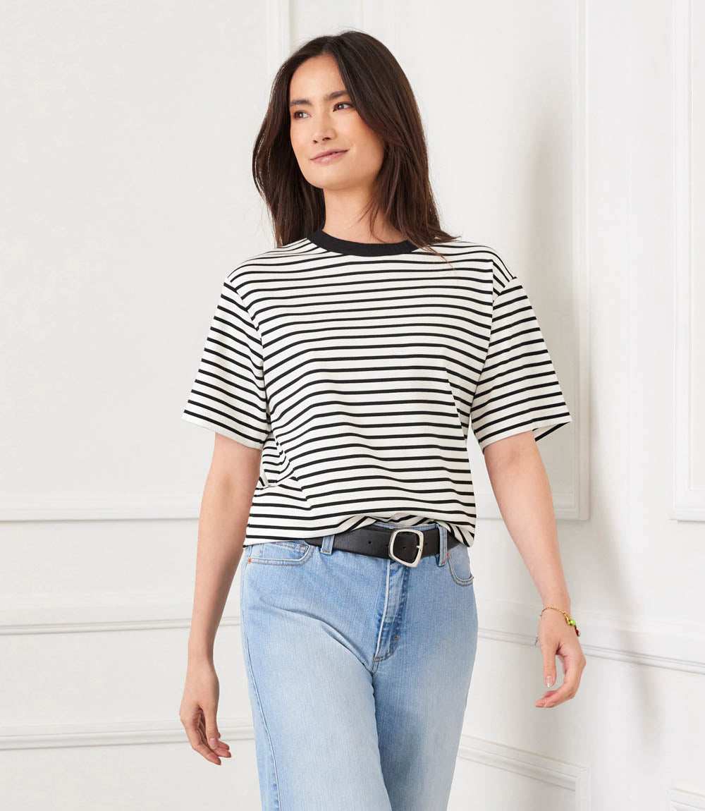 Woman wearing a black and white striped shirt and light blue jeans against a white background