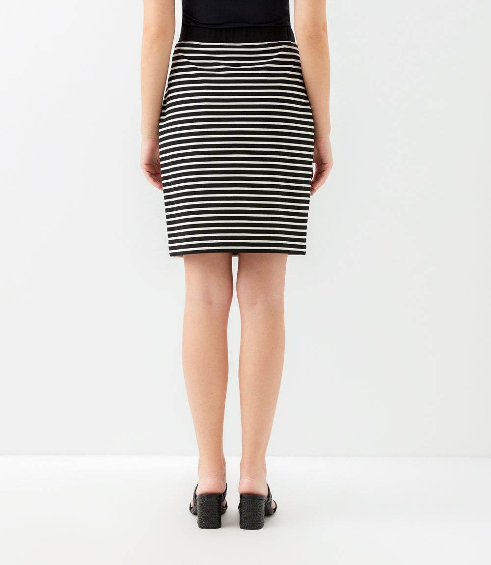 A model shown from the back wearing a black and white horizontally striped pencil skirt, paired with a black top and black mule sandals, against a plain white studio background.