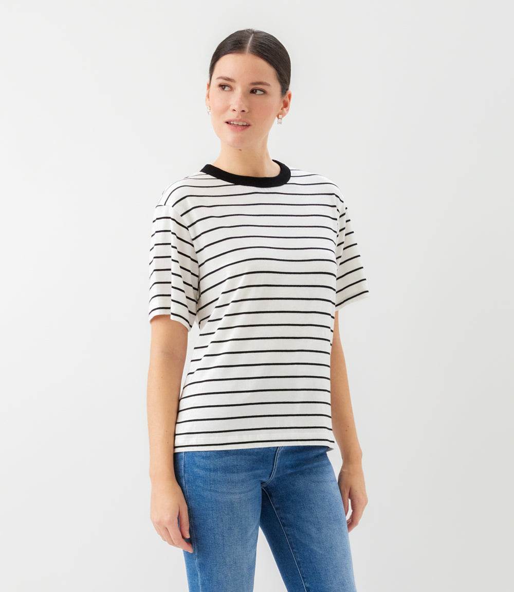 Woman wearing a black and white striped shirt with blue jeans on a white background