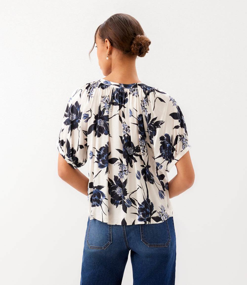 Person wearing a floral blouse and blue jeans on a white background