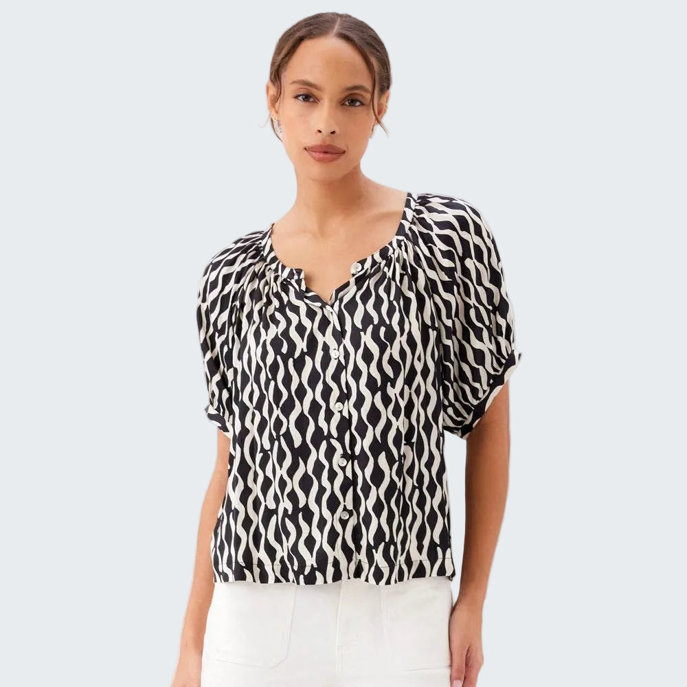 Woman wearing a black and white patterned blouse against a white background