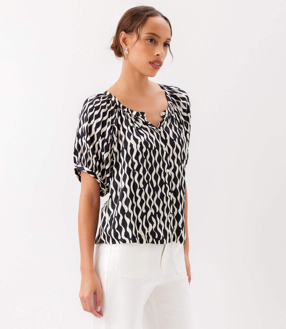 Woman wearing a black and white patterned blouse on a white background