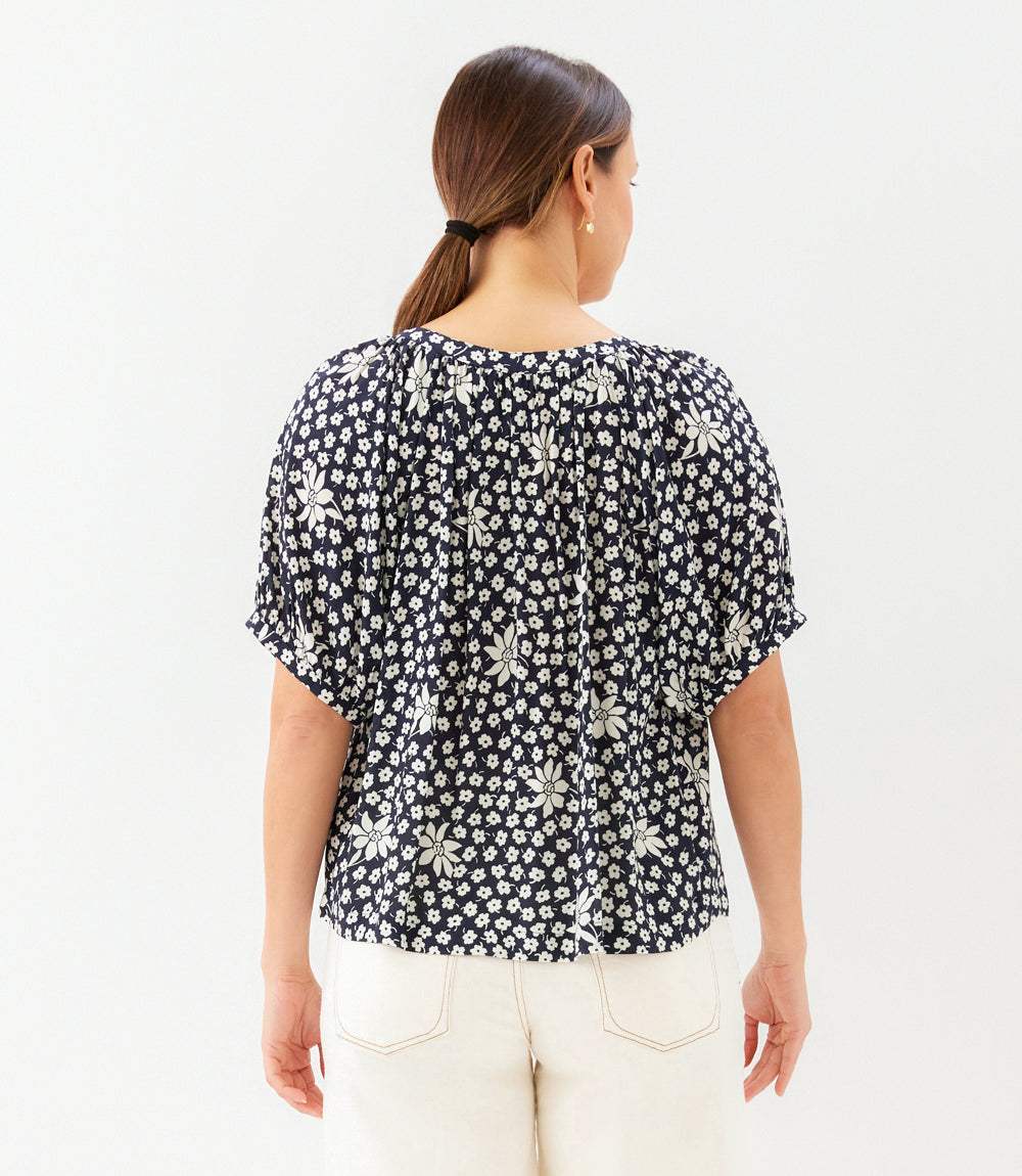 Woman wearing a black floral blouse against a white background