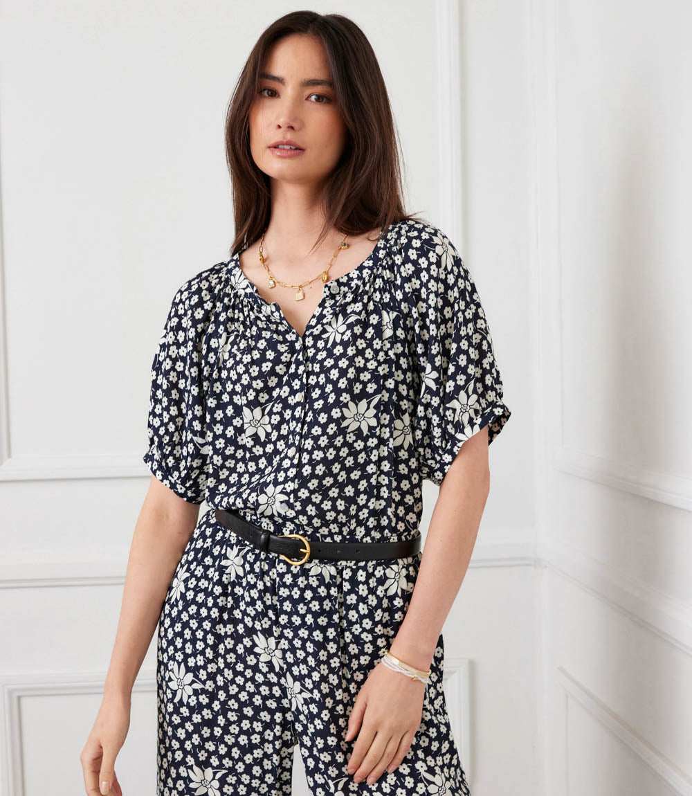 Woman wearing a black floral dress against a white wall