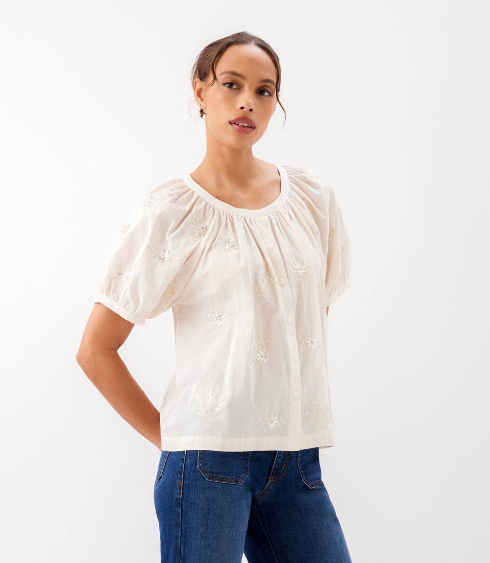 Woman wearing a white blouse with short sleeves and blue jeans on a white background