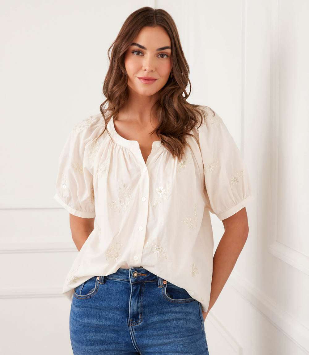 Woman wearing a white blouse and blue jeans against a white background