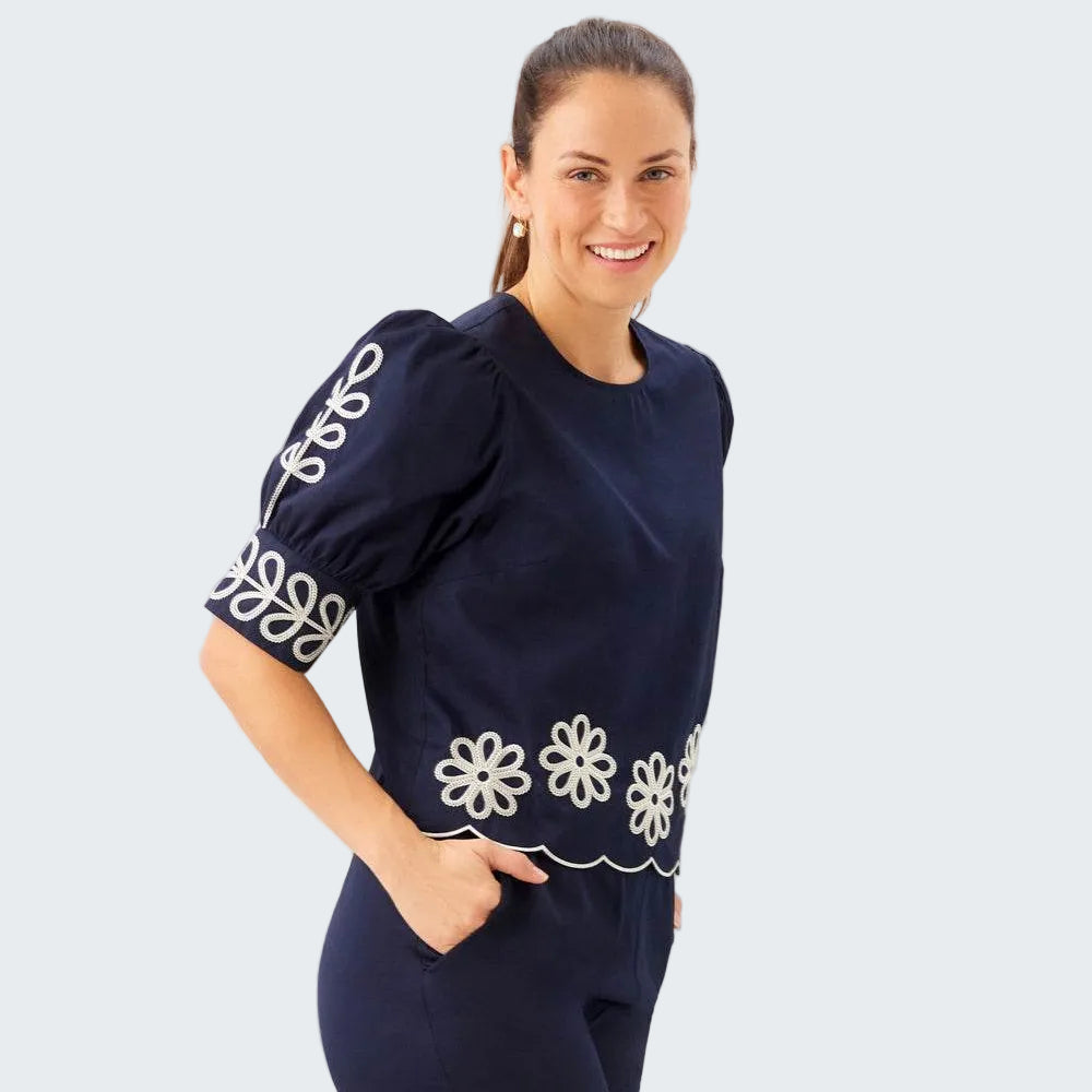 Woman wearing a navy outfit with white floral patterns on a plain background
